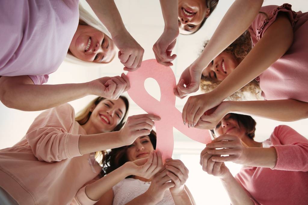 Women holding pink paper ribbon, bottom view. Breast cancer awar