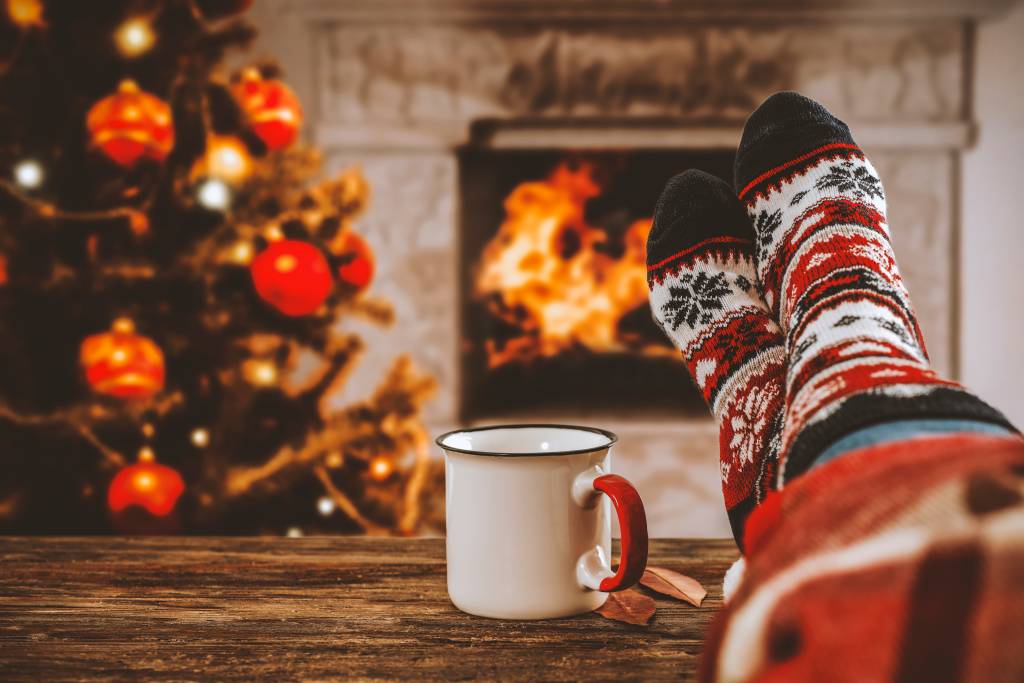 Woman legs with christmas socks and fireplace in home interior