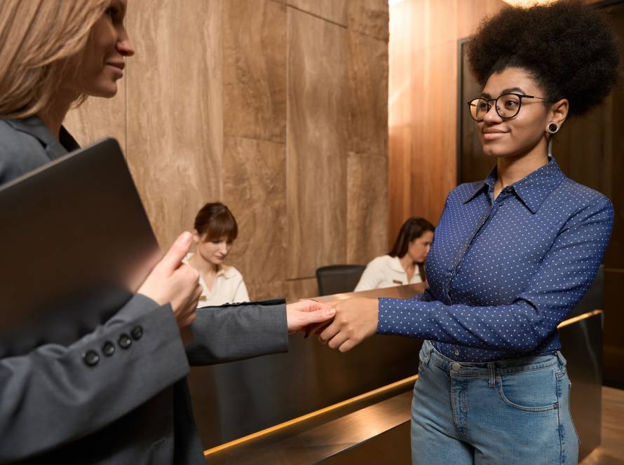 Administrative support of african american woman shaking the hand of white woman