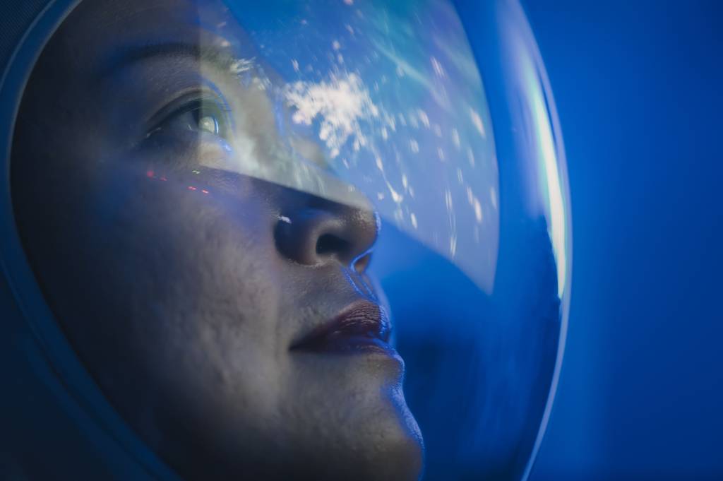 Space woman looking through a glass into the outer dimensions