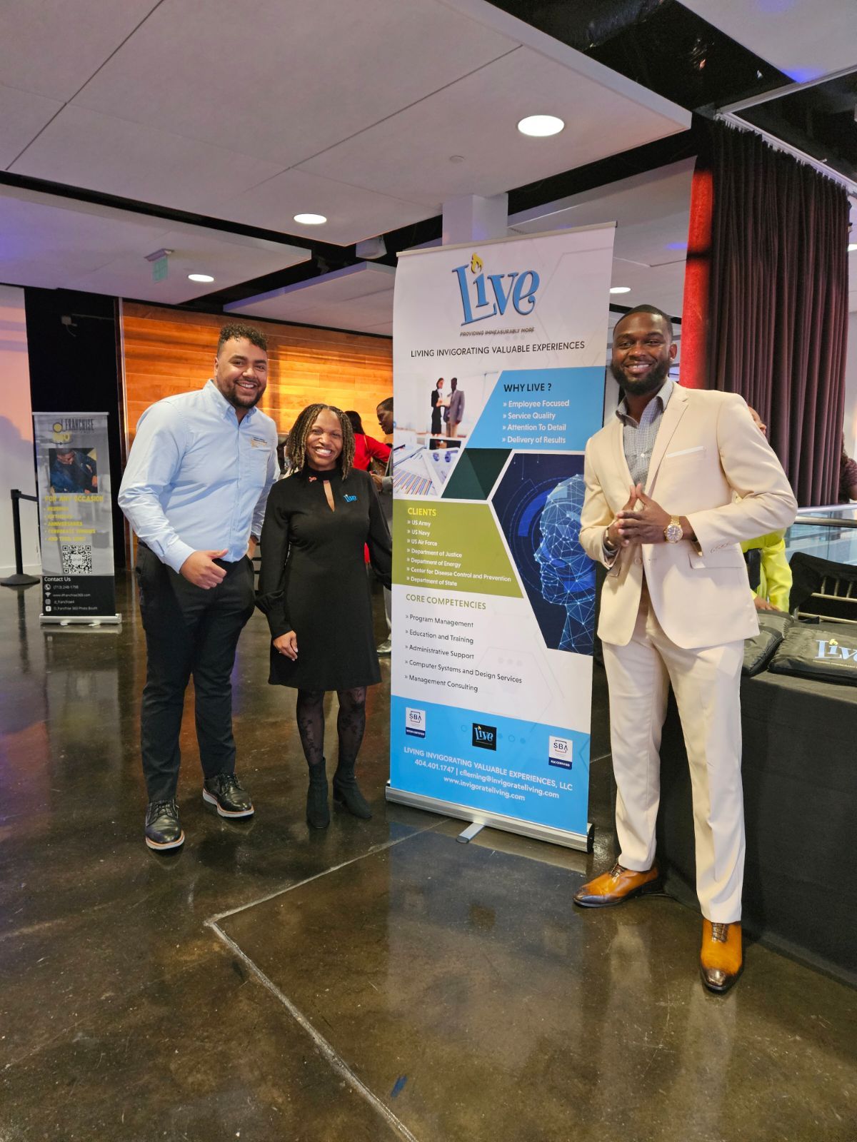 andre, crystal, and client standing in front of live banner